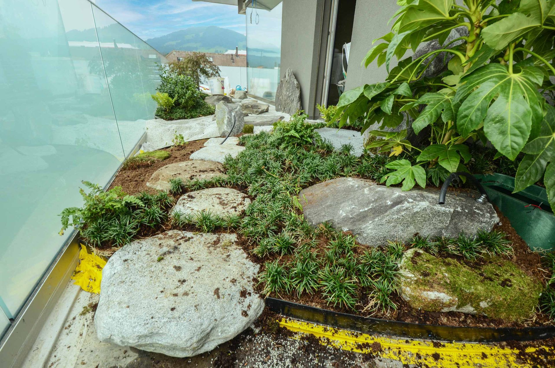 Un giardino con rocce e piante su un balcone.