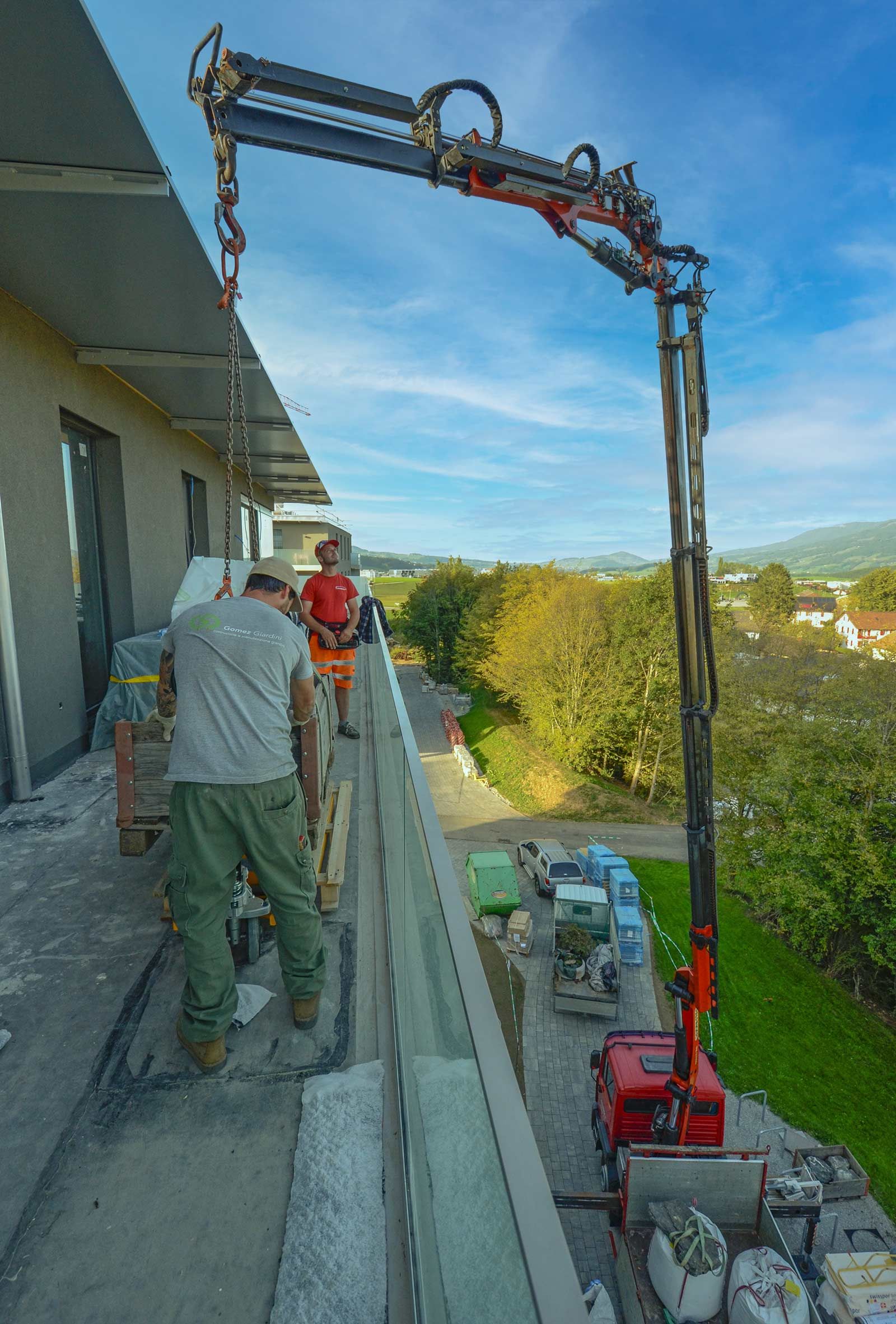 Un uomo è in piedi su un balcone e scarica materiale da una gru.