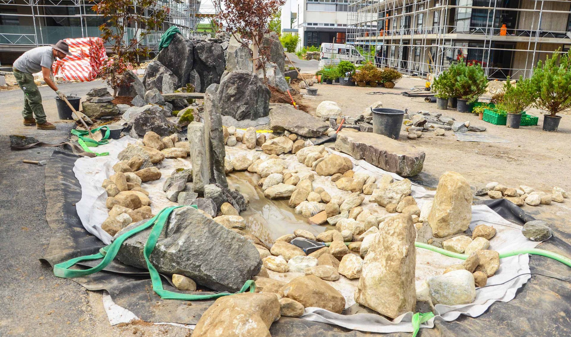Un uomo sta lavorando in un giardino roccioso con una pala.