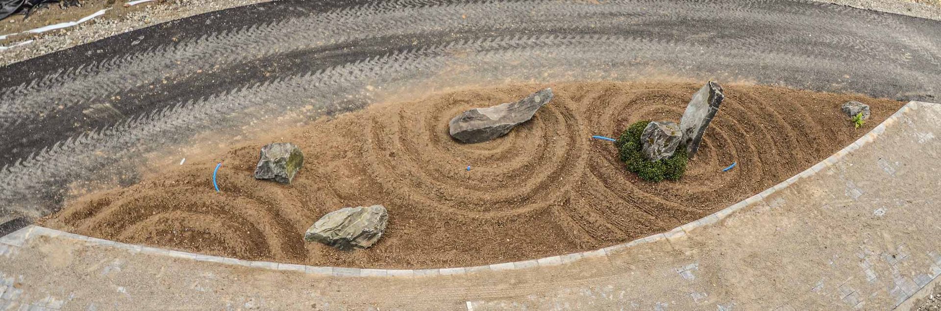 Un piccolo giardino roccioso in mezzo a una strada sterrata.