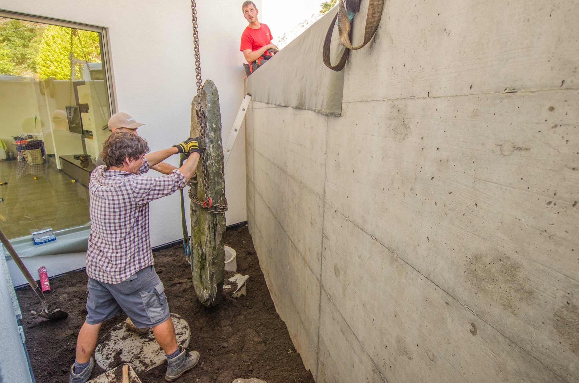 Un uomo è in piedi davanti a un muro di cemento posando una grande roccia.