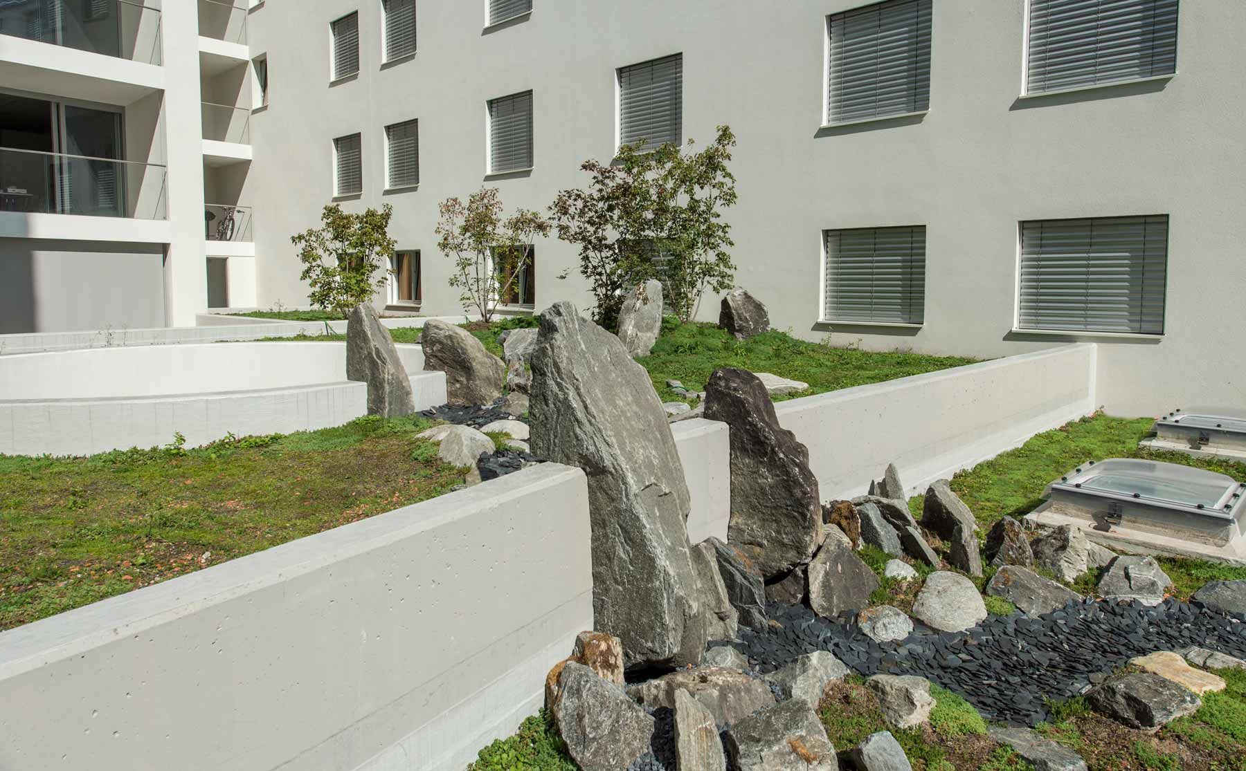 Un edificio con molte finestre e rocce di fronte in un giardino giapponese.