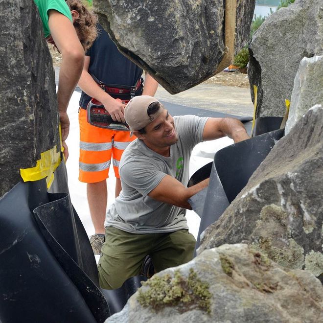 Un uomo che indossa un cappello sta lavorando su una grande roccia