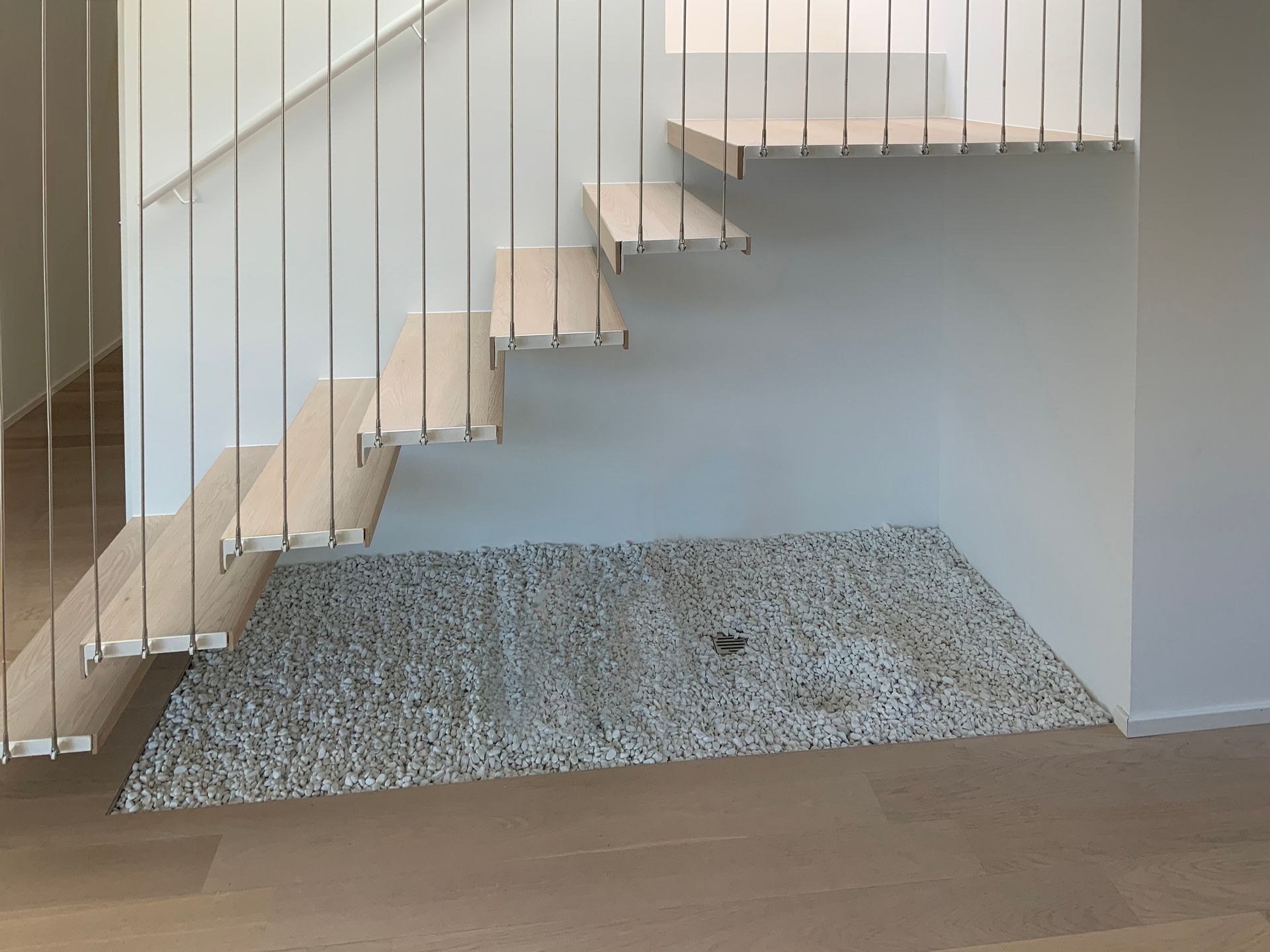 Una scala con ringhiera in acciaio inossidabile e gradini in legno in una casa.