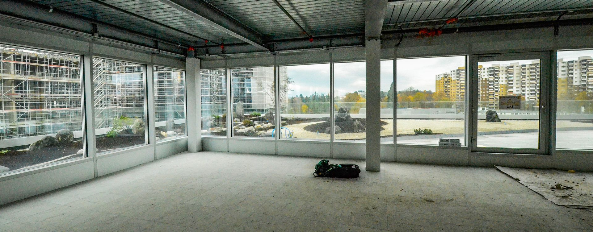 Una stanza vuota con molte finestre e un pavimento di cemento.