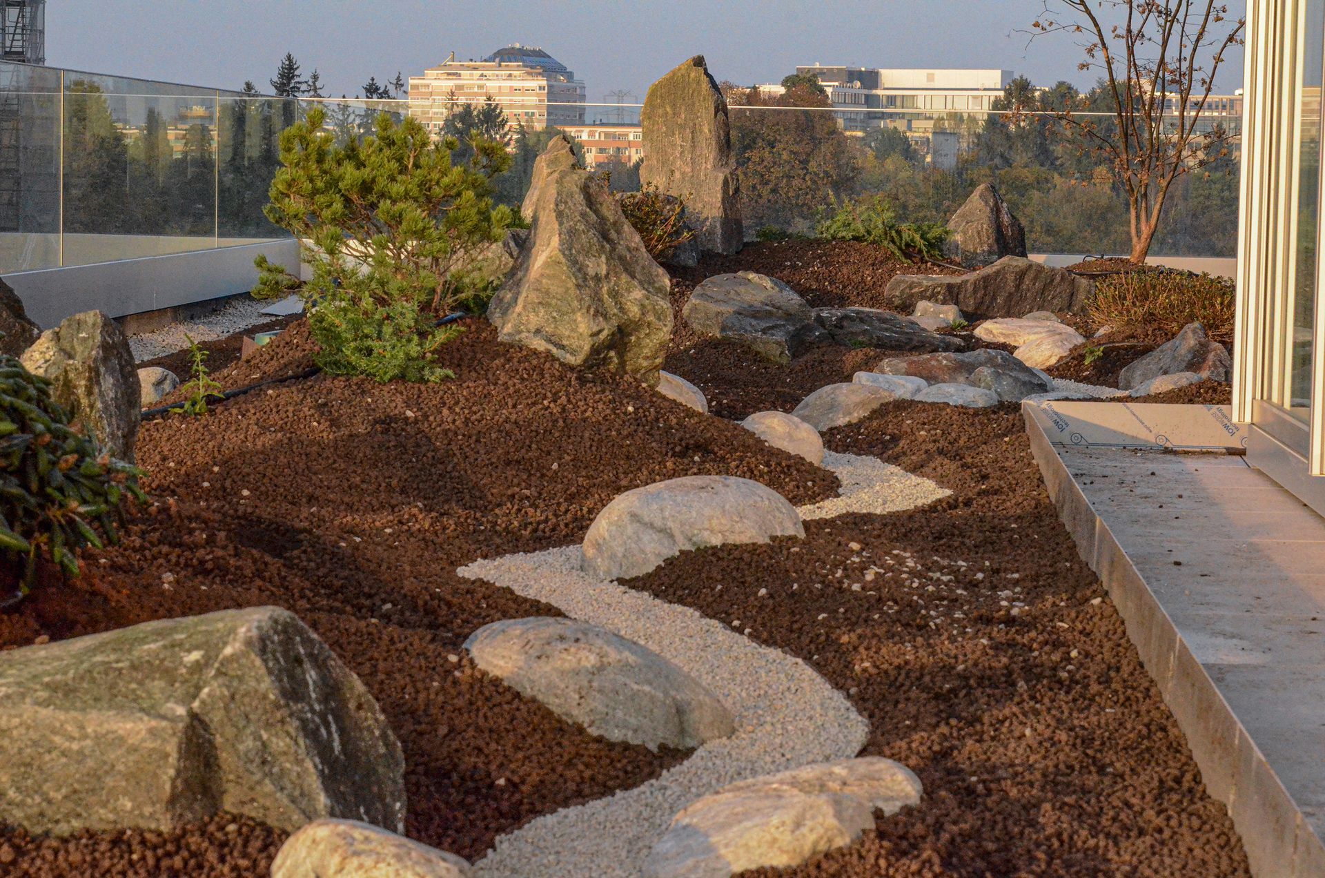 Un rigoglioso giardino verde su una terrazza con rocce e piante e una città sullo sfondo