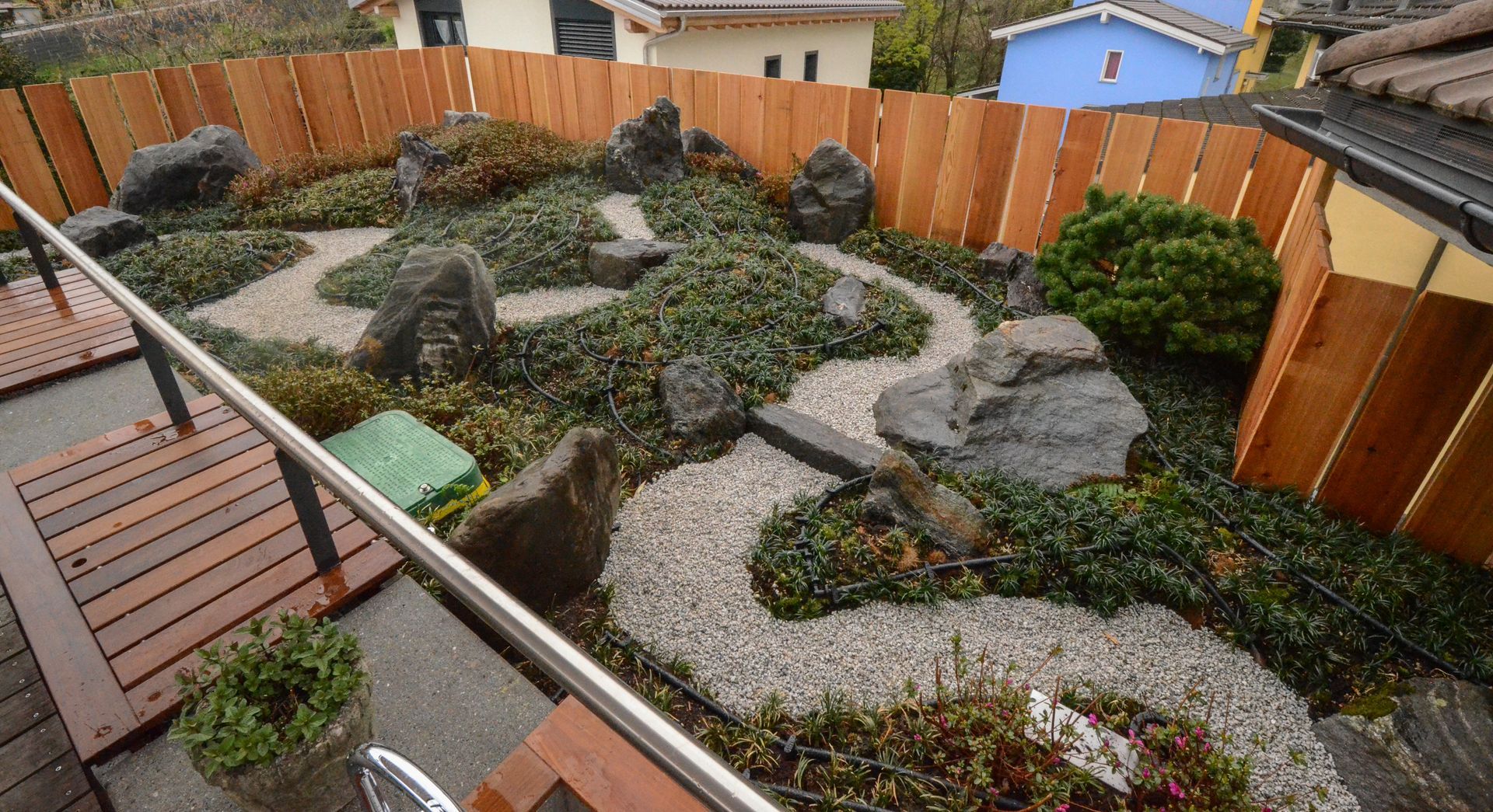 Una staccionata di legno circonda un giardino con rocce e piante