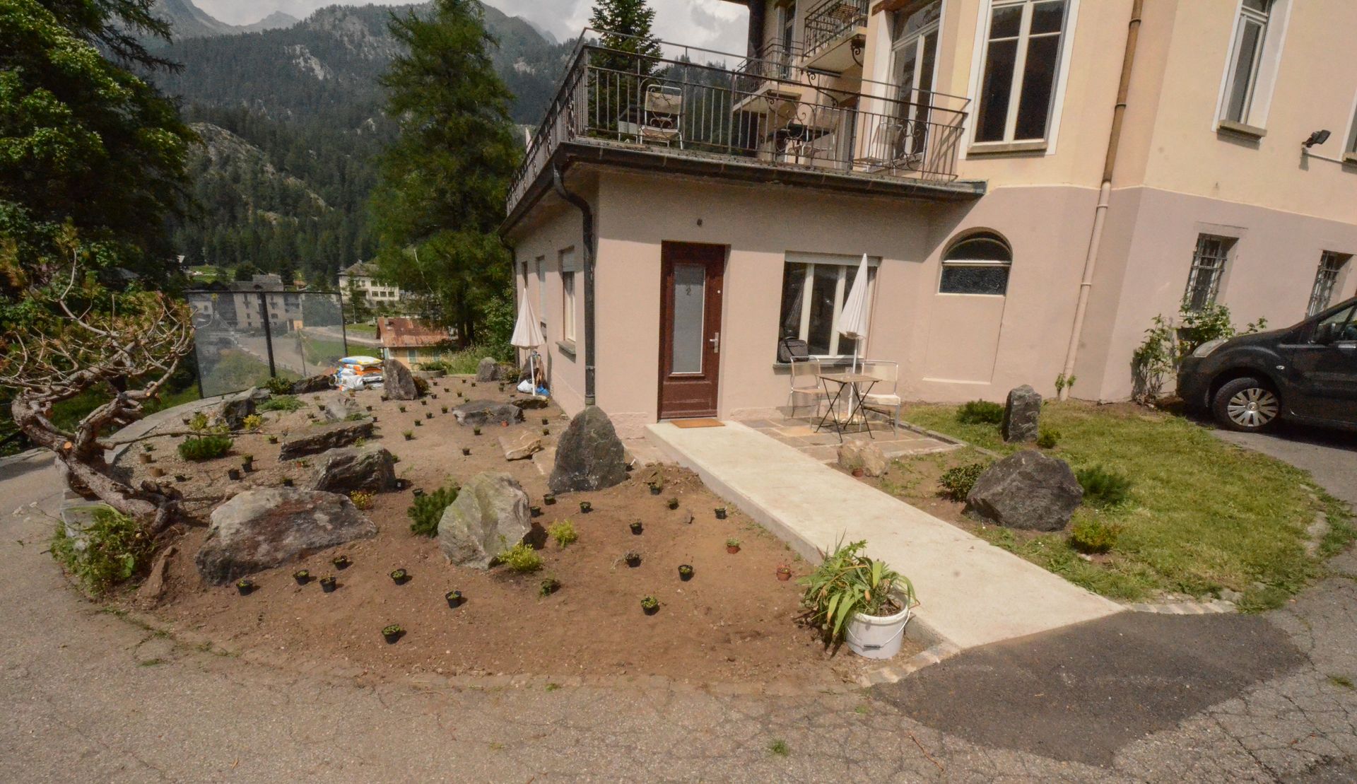 Una casa con aiuola e un'auto parcheggiata davanti