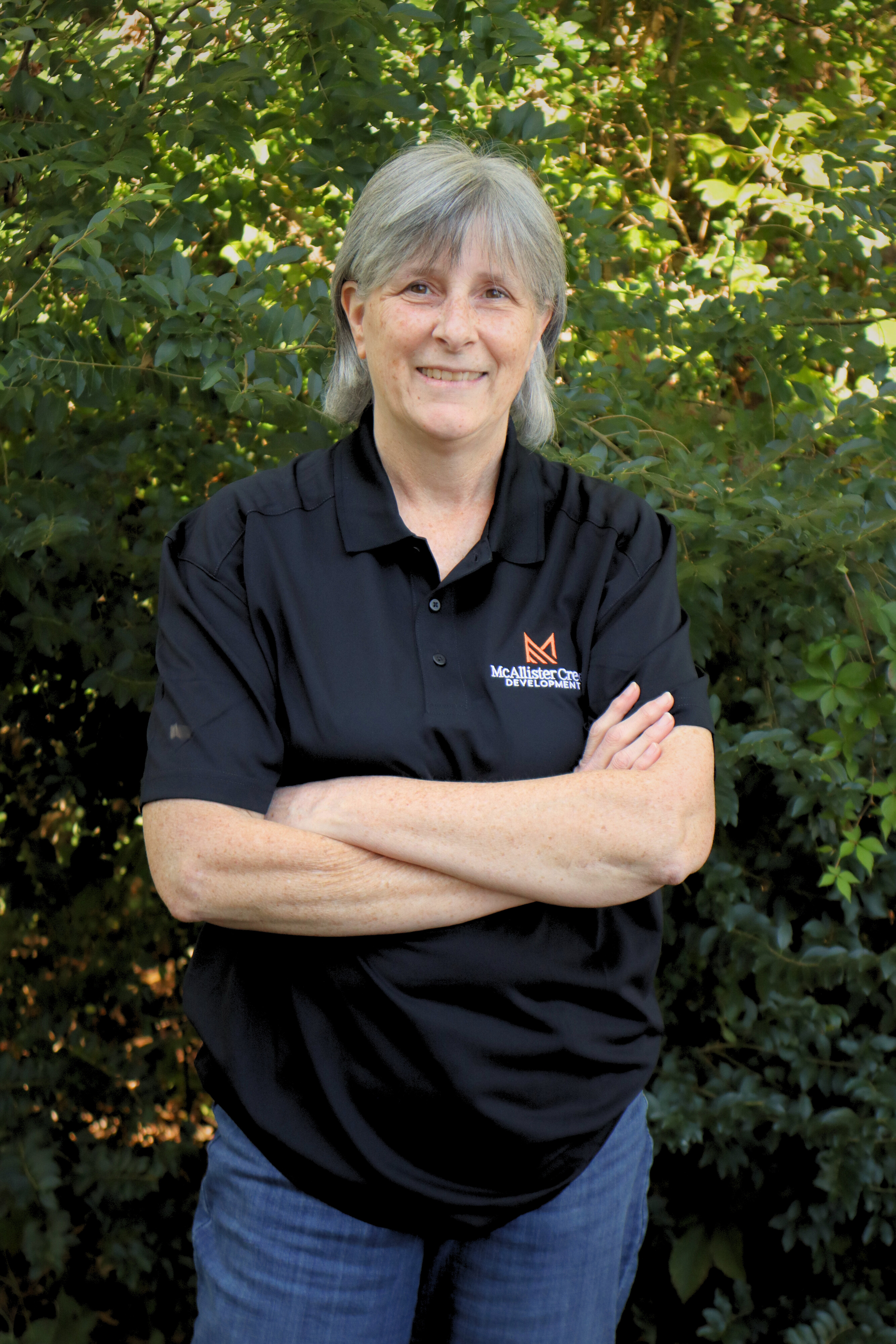 woman with crossed arms in front of tree