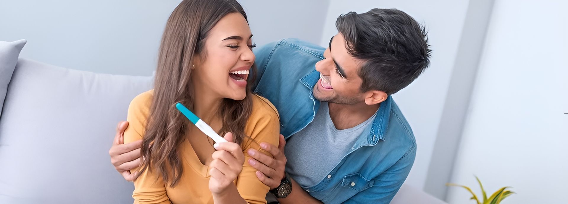 A Man and a Woman Are Sitting on a Couch Holding a Pregnancy Test — Scott Martin Acupuncture Mackay In Cannonvale, QLD