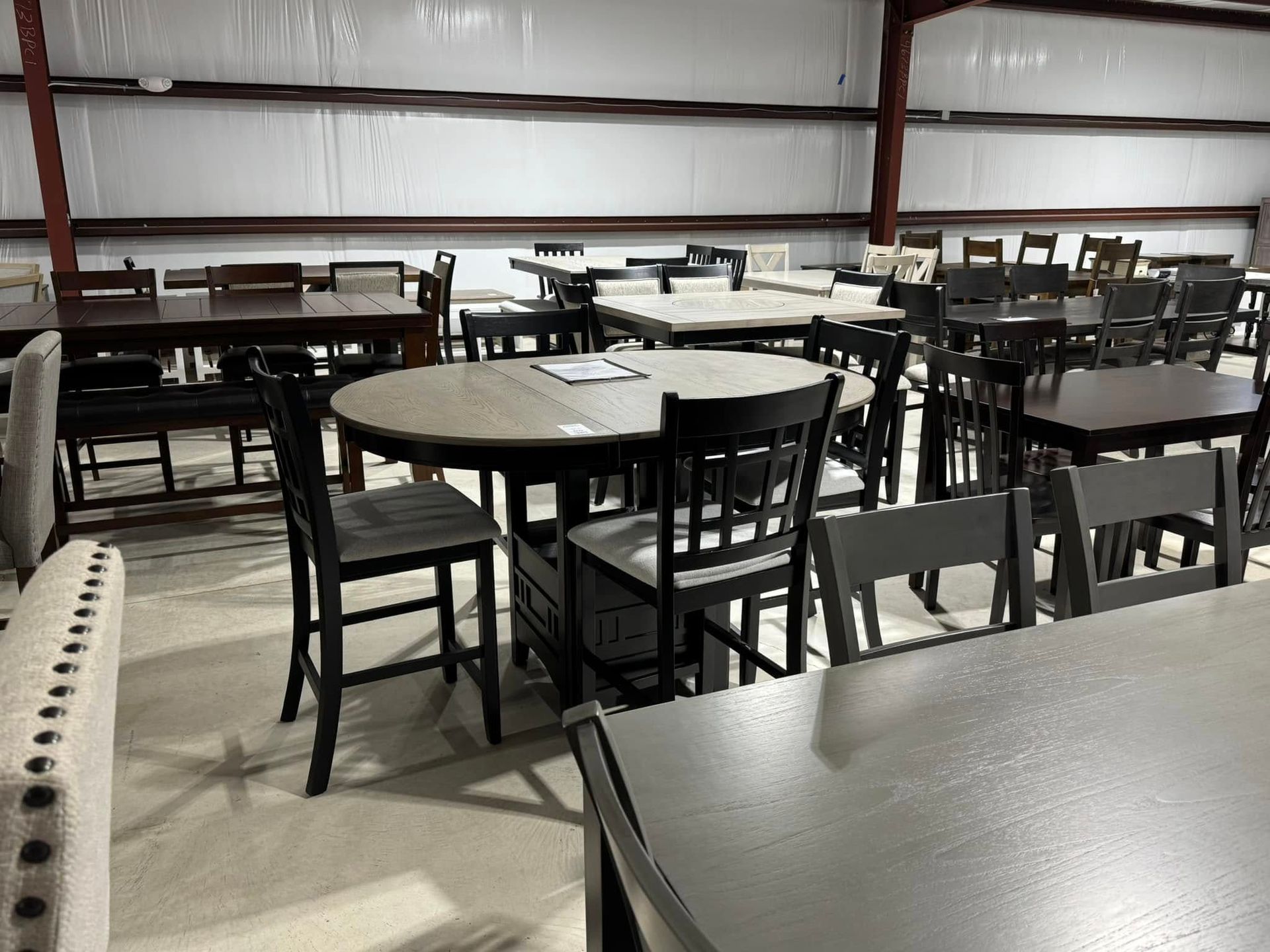 Furniture showroom filled with dining tables and chairs in various styles and finishes.