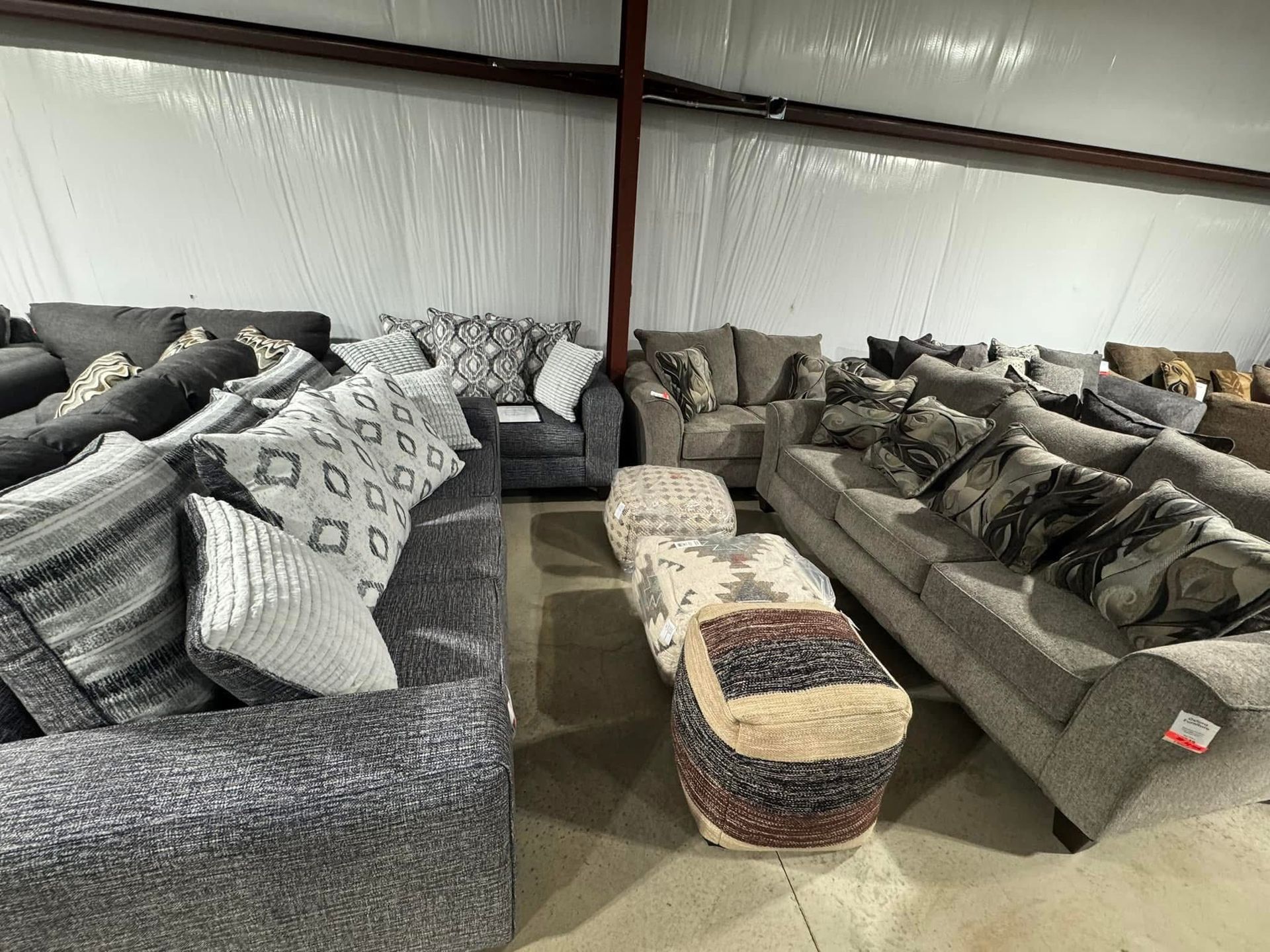 Sofas and ottomans in a warehouse, various shades of gray.