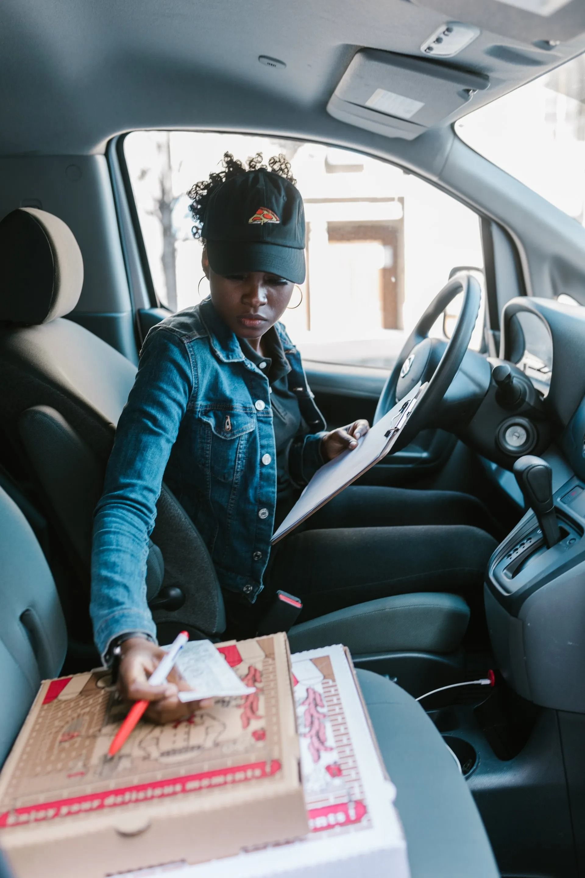 Person in a car handing a package to someone outside the vehicle.