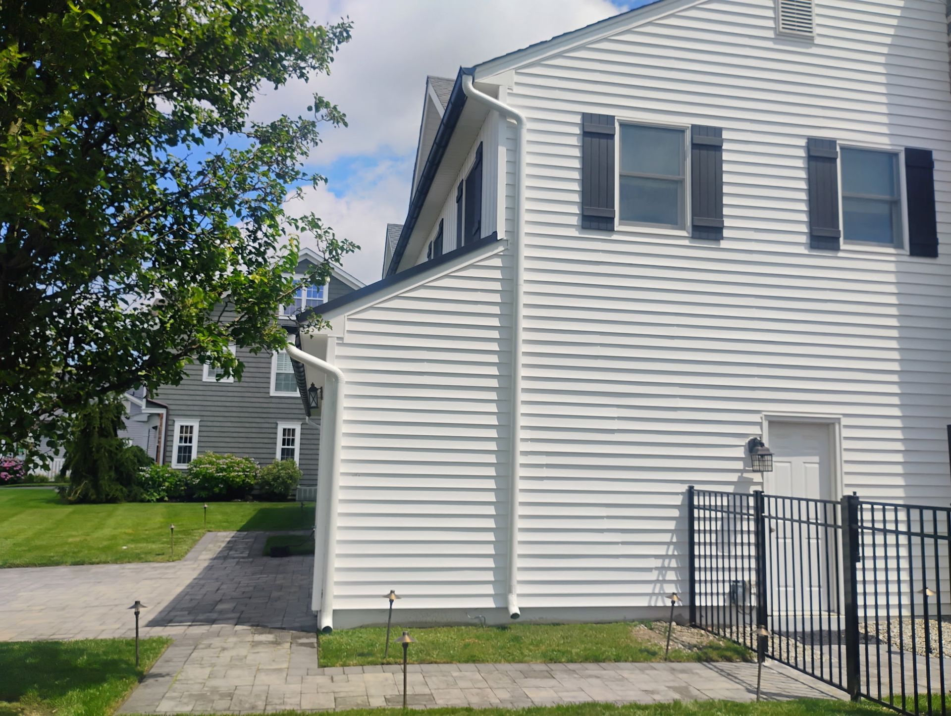 Side view of residential home with new white siding and exterior renovation work.
