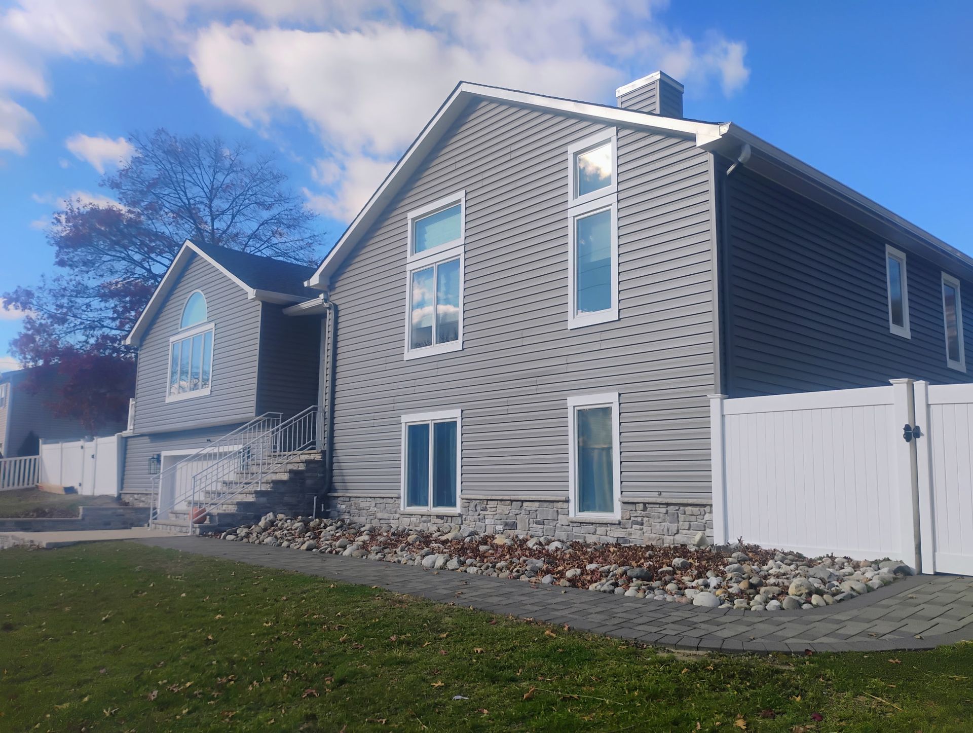 Gray house with white trim and fence; blue sky.