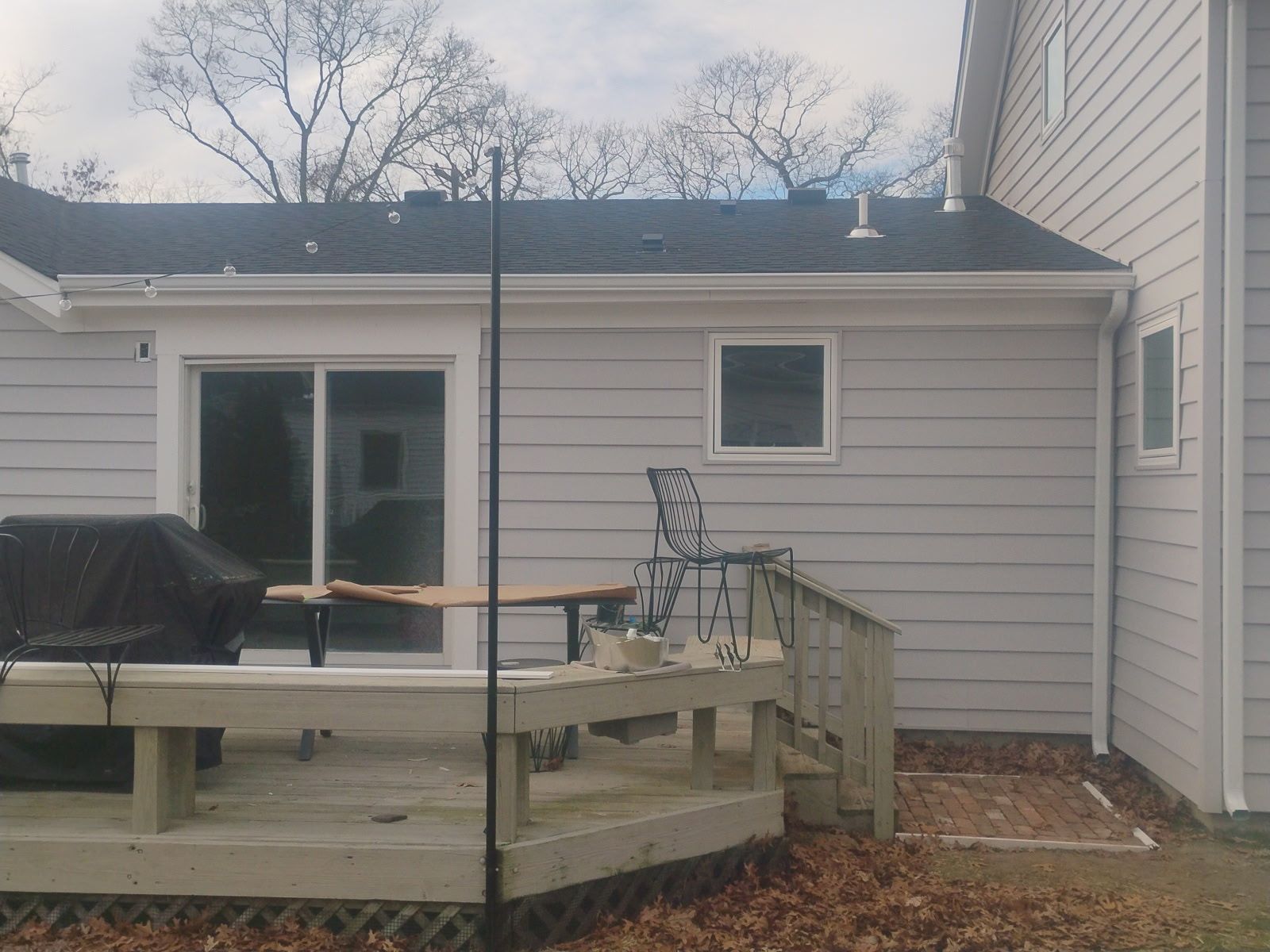 Exterior of a house with light gray siding, a deck, and a sliding glass door.