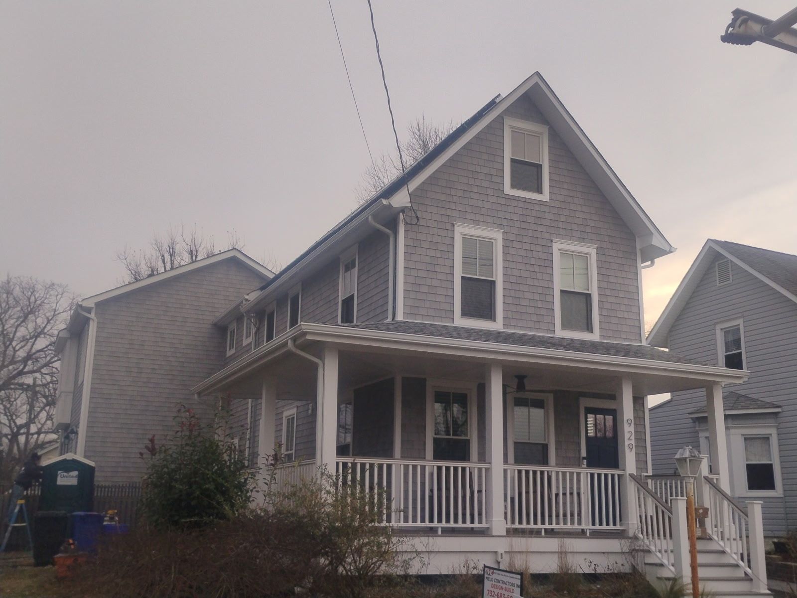 Two-story gray house with porch and white trim on a cloudy day.