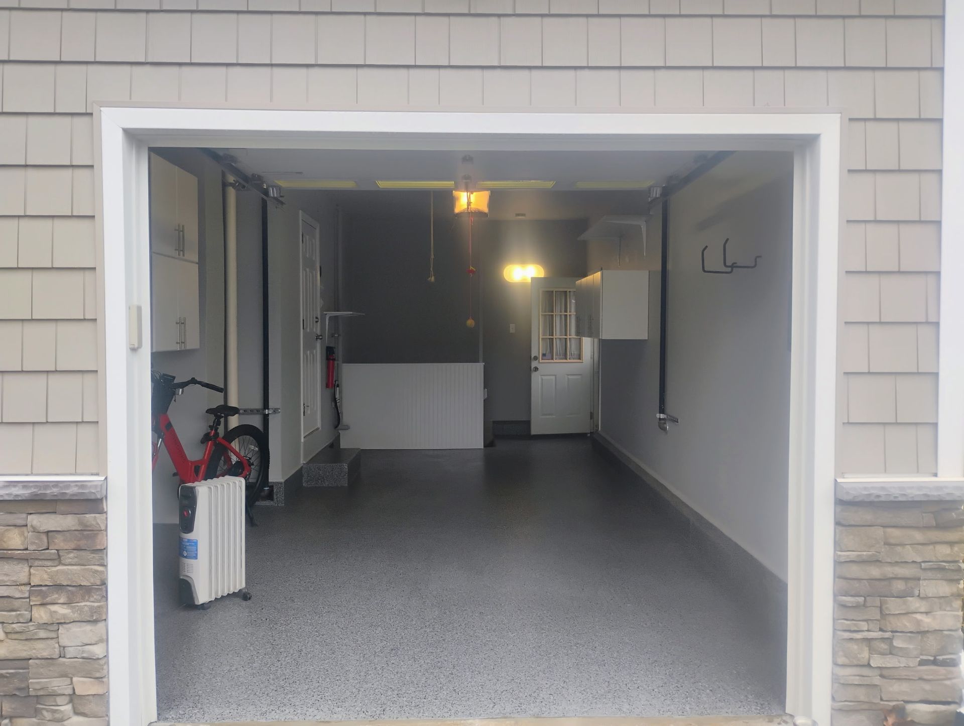 Open garage with gray speckled floor, white walls, and storage cabinets.