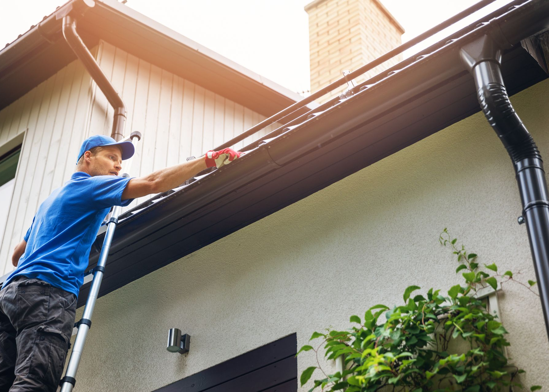 Technician cleaning residential gutters, part of gutter maintenance services in NJ.
