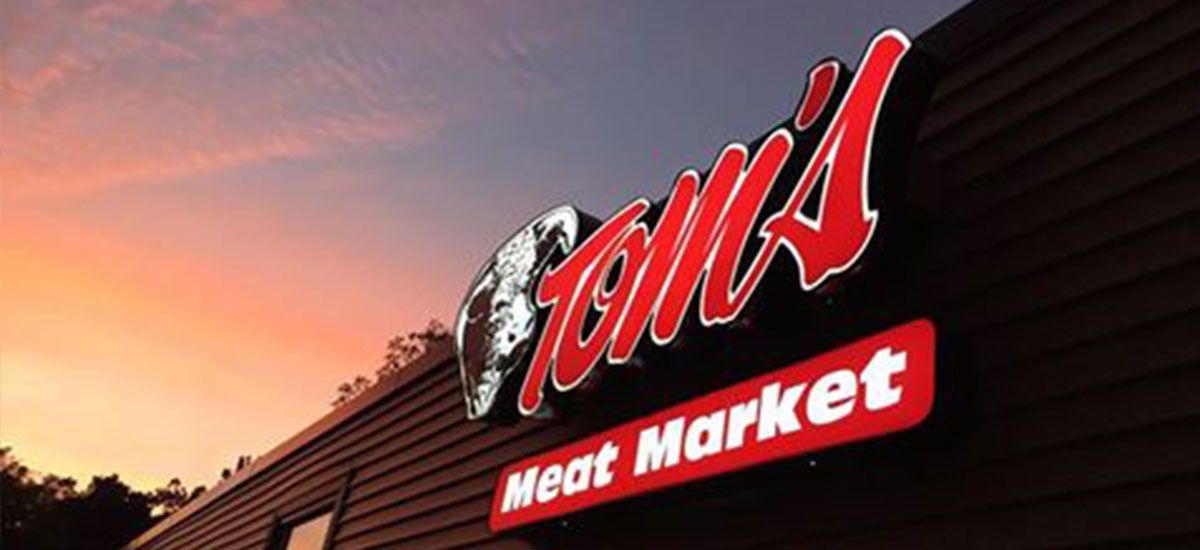 A meat market sign is on the side of a building.