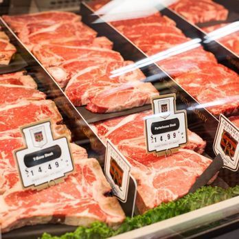 A variety of meats are displayed in a butcher shop.