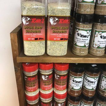 A shelf filled with bottles of tom 's special blend seasoning.