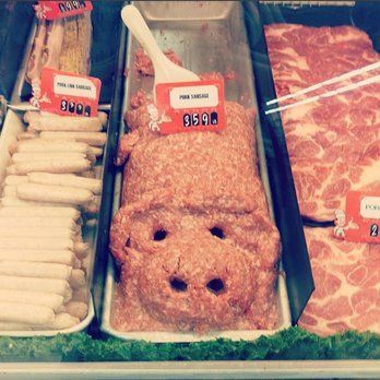 A display case filled with meats and sausages with a meatball in the shape of a pig.