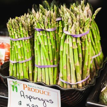 A bunch of asparagus wrapped in purple ribbons are sitting on a table.