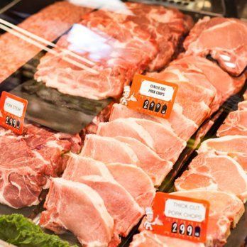 A variety of pork chops are displayed in a butcher shop.