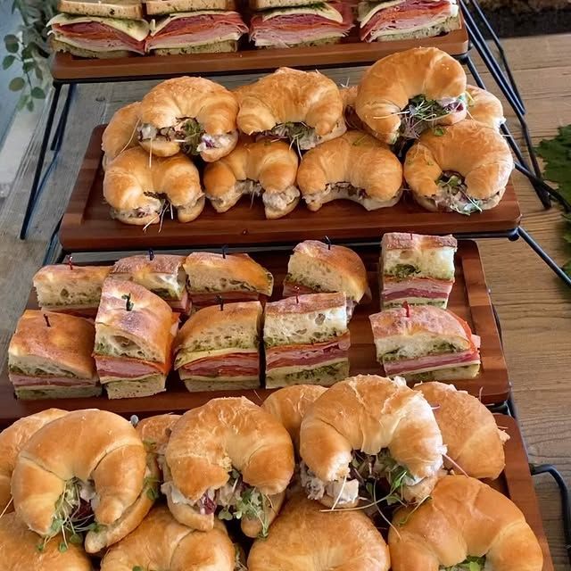 A display of sandwiches and croissants on wooden trays