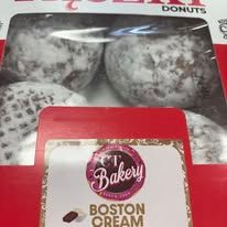 A box of boston cream donuts is sitting on top of a red table.