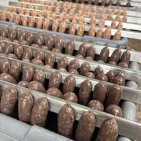 A bunch of sausages are sitting on a conveyor belt in a factory.