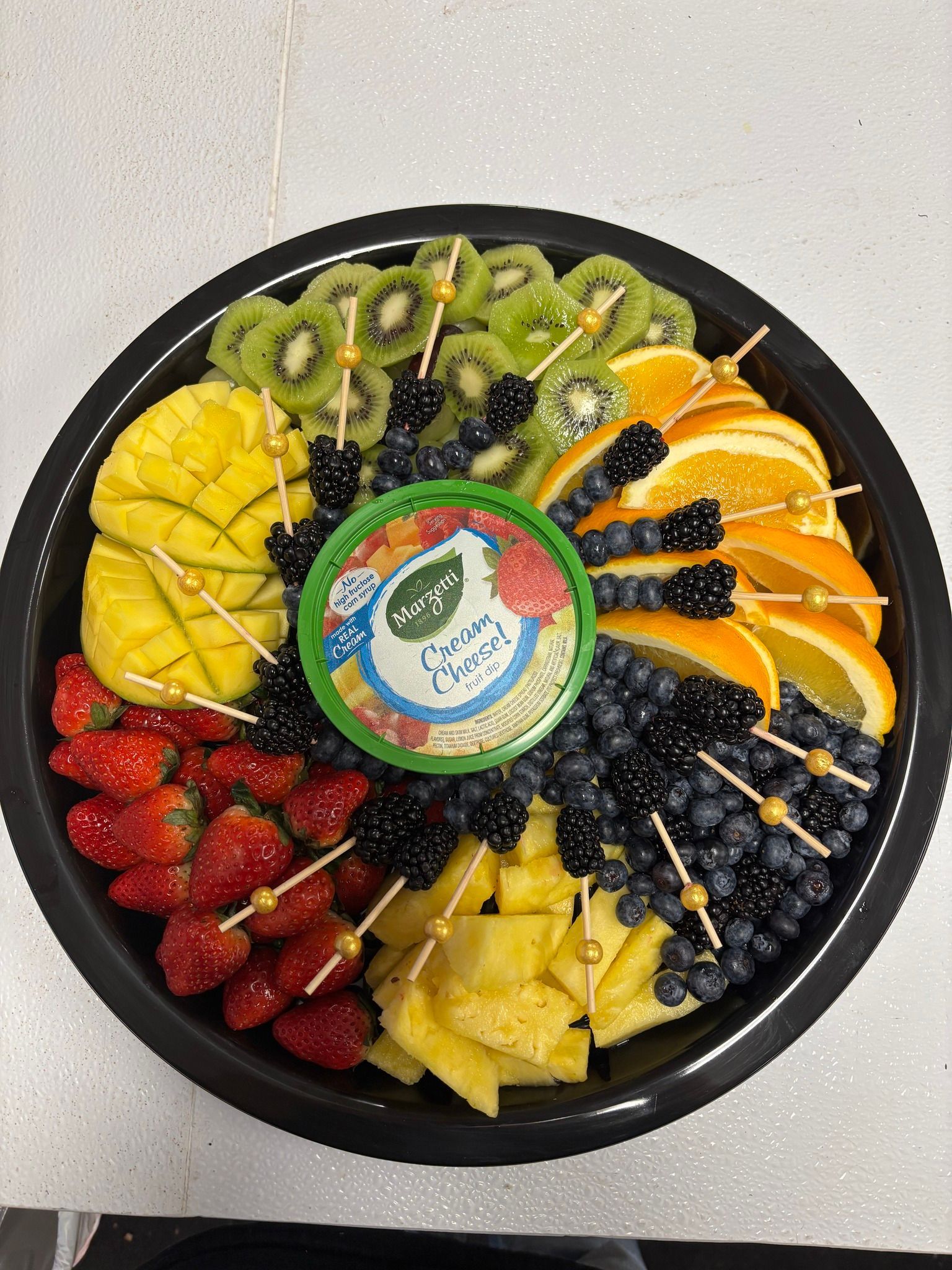 A tray of fruit with toothpicks in it