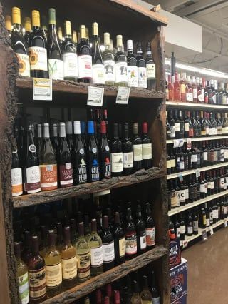 A shelf filled with lots of wine bottles in a liquor store.