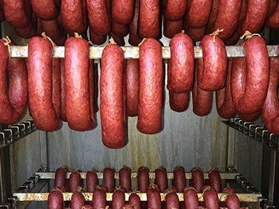 A bunch of sausages are hanging from a rack in a room.