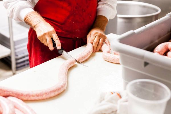 A person is cutting a sausage on a cutting board.