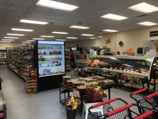 The inside of a grocery store with a display case and shopping carts.