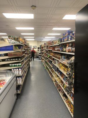 A long aisle of a grocery store filled with lots of shelves.