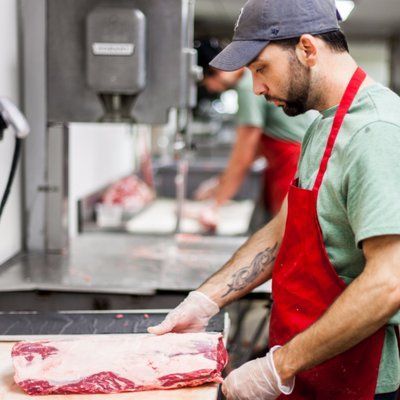 A man is cutting a piece of meat on a cutting board.