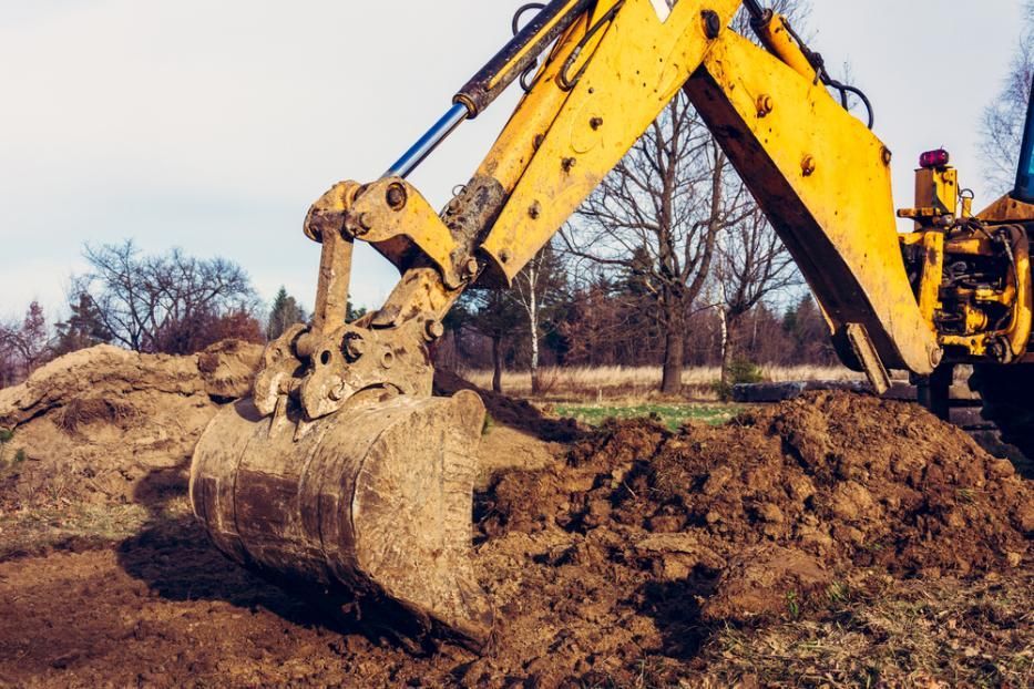 A Yellow Excavator Is Digging a Pile of Dirt in A Field — J Newton Excavations in Bentley Park, QLD