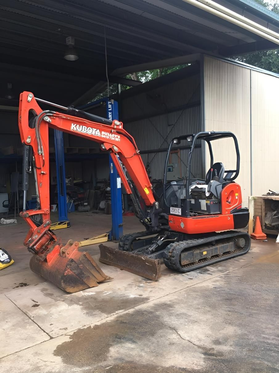 A Small Red Excavator Is Parked in Front of A Garage — J Newton Excavations in Bentley Park, QLD