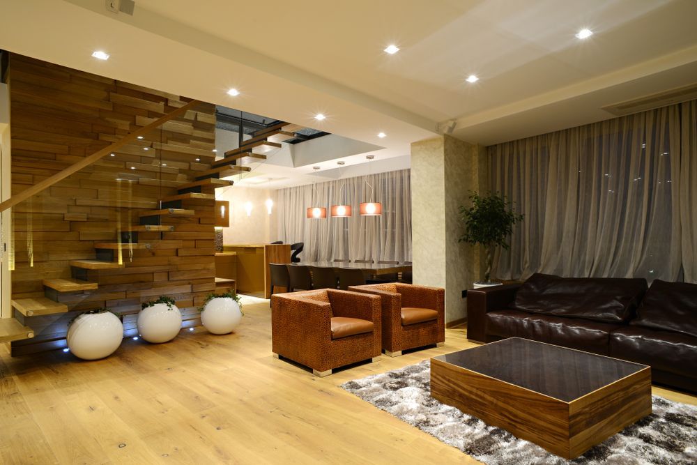 Modern Living Room With Wooden Staircase, Leather Furniture, and Light Wood Flooring — DC Active Electrical in Brighton, QLD