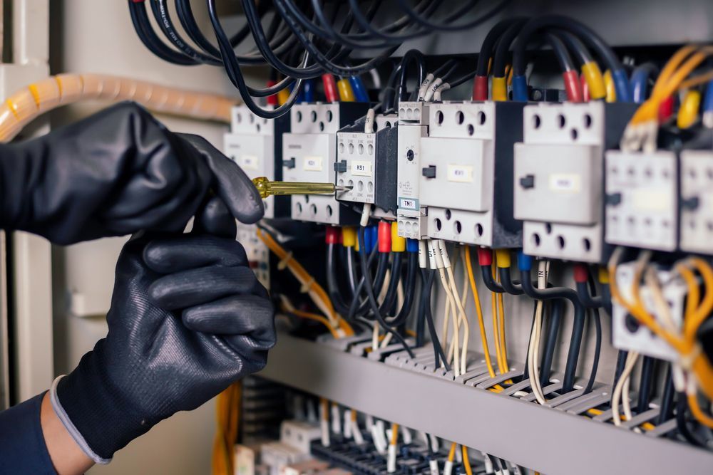 Electrician With Gloved Hands Using a Screwdriver on Electrical Panel Wiring — DC Active Electrical in Bracken Ridge, QLD
