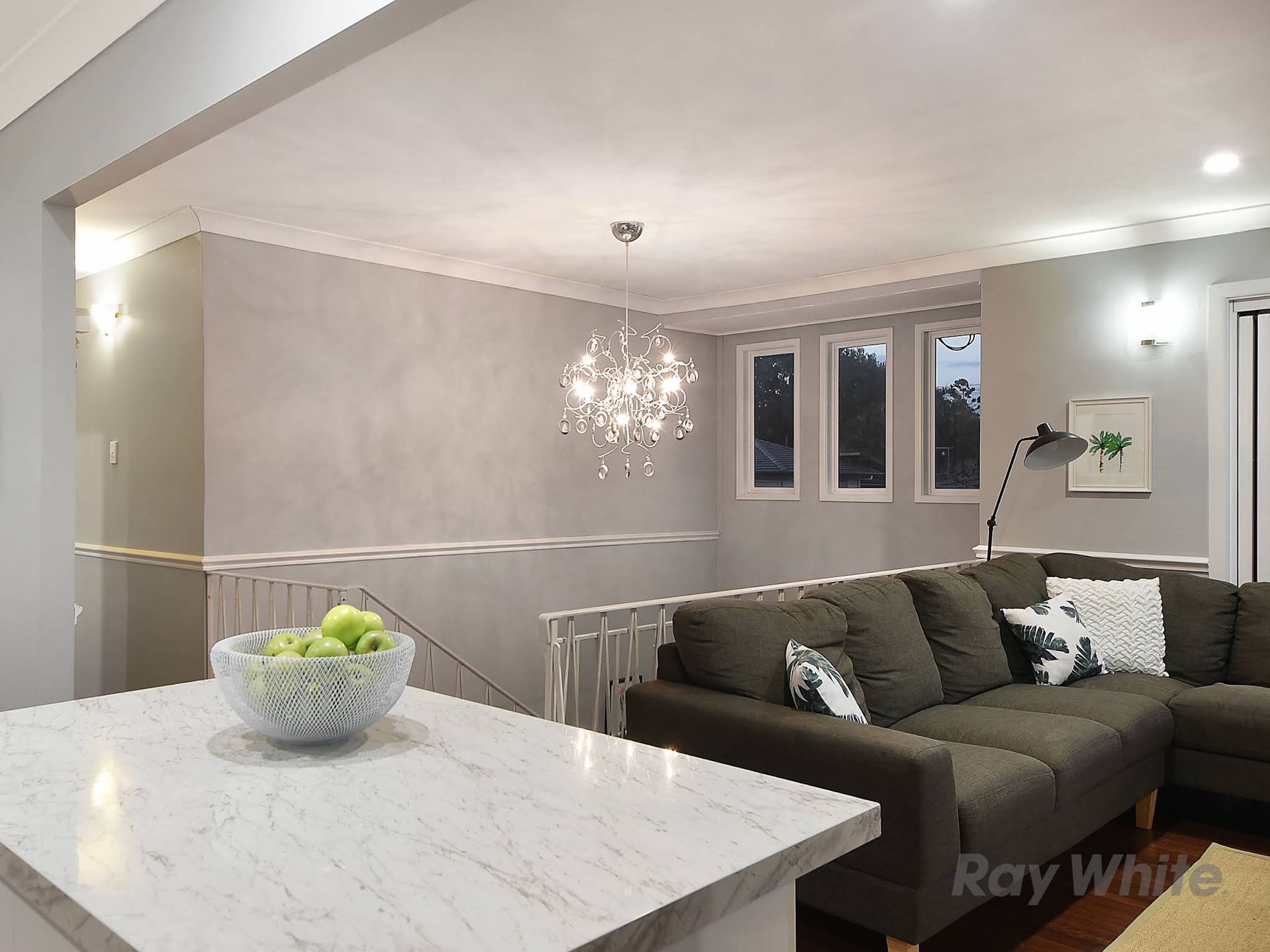 Modern Living Room With Sectional Sofa, Chandelier, and a Countertop With Fruit — DC Active Electrical in Brighton, QLD