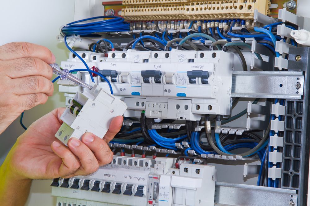 Electrician Installing a Circuit Breaker in a Fuse Box, Using a Screwdriver — DC Active Electrical in Redcliffe, QLD