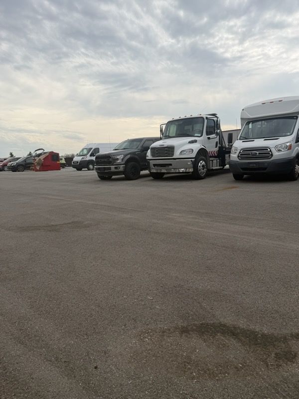 Parked trucks and vans on a wide asphalt lot under a cloudy sky