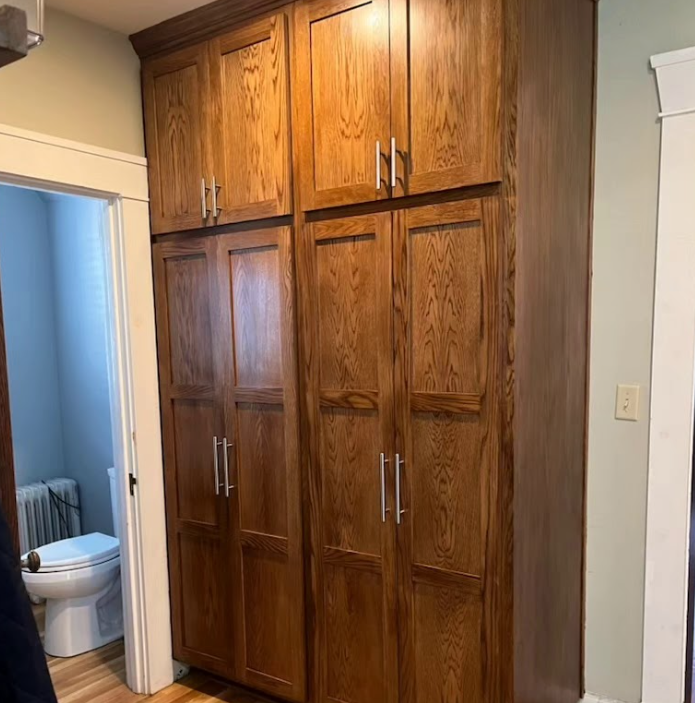 A bathroom with a toilet and a large wooden cabinet.