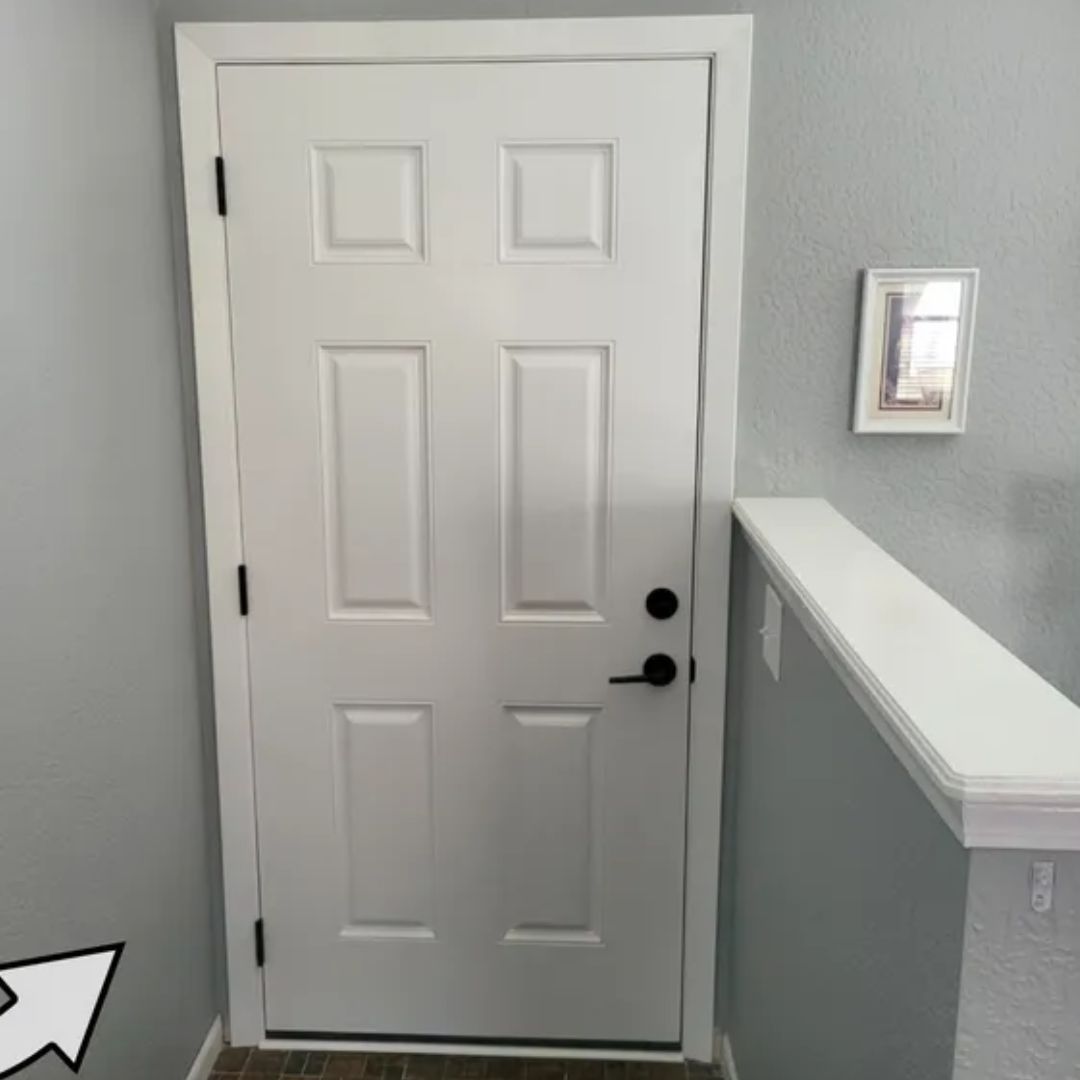 A white door in a hallway with an arrow pointing to the right