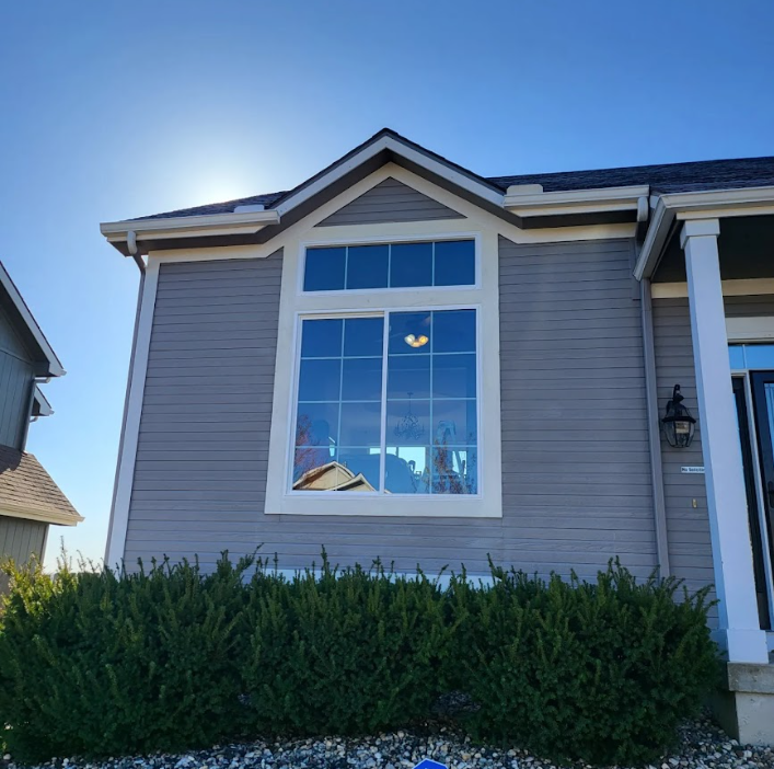 A house with a large window and a blue sky in the background
