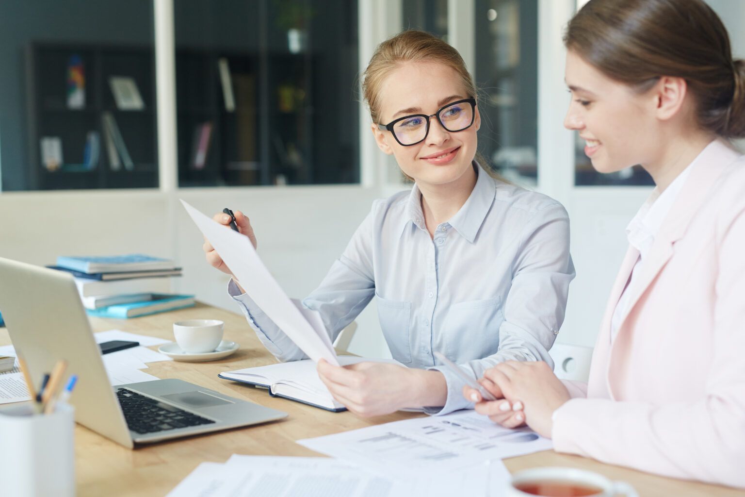 Deux femmes sont assises à une table et regardent un morceau de papier.